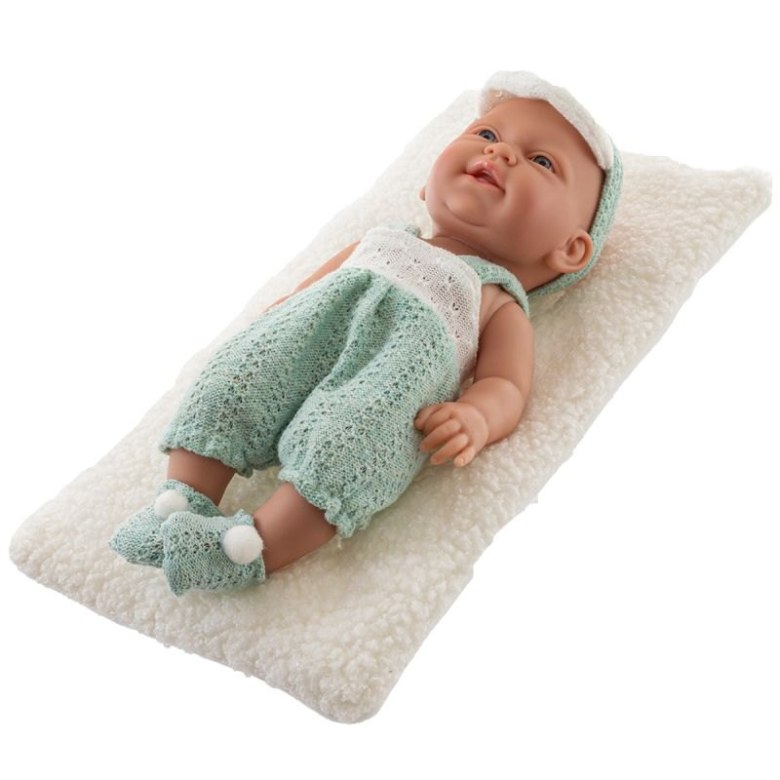 Lalka niemowlę leżąca na miękkiej poduszzcze w zielonym ubranku
