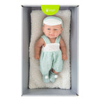 Lalka Puro Baby w miętowym ubranku leżąca na poduszce
